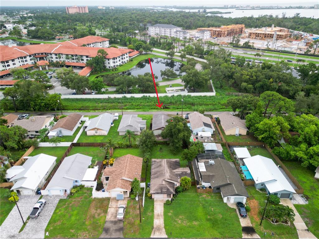 An aerial view shows a suburban neighborhood with single-family homes near a pond and construction — 2227 BENSON STREET, SARASOTA, FL