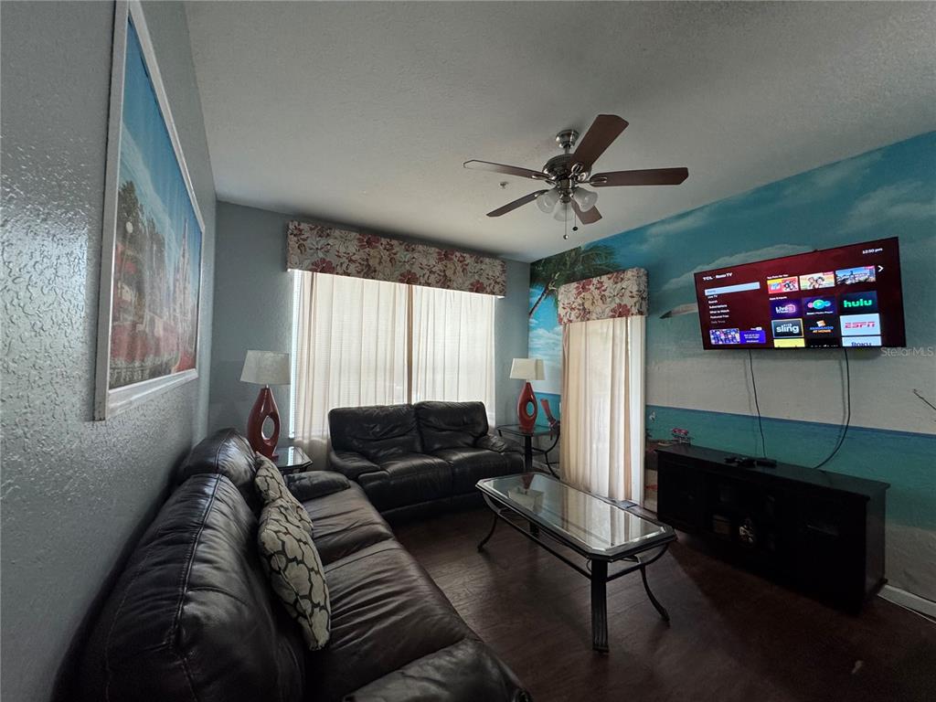 A living room features dark leather sofas, a glass coffee table, and a wall-mounted television — 2821 ALMATON LOOP UNIT 205, KISSIMMEE, FL