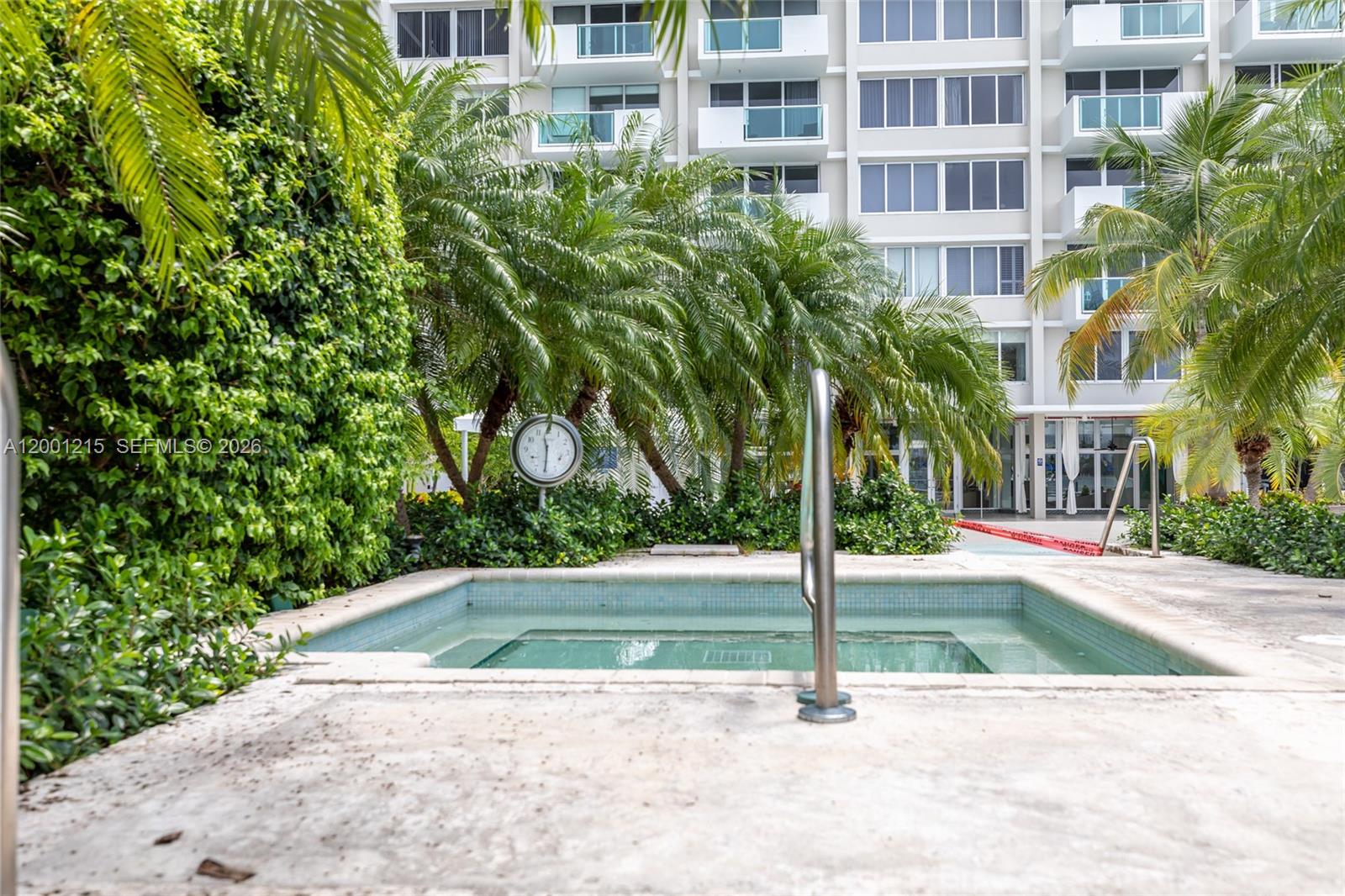 A small outdoor hot tub is situated on a concrete patio near palm trees — 1200 West Ave, Miami Beach FL 33139, MIAMI BEACH, FL