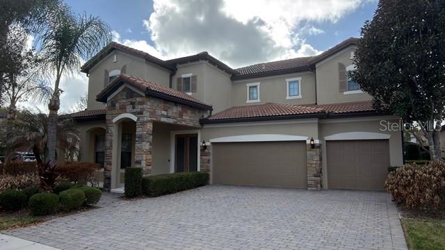 A two-story house with a stone-accented entryway, a three-car garage, and a paved driveway — 9442 ROYAL ESTATES BOULEVARD, ORLANDO, FL