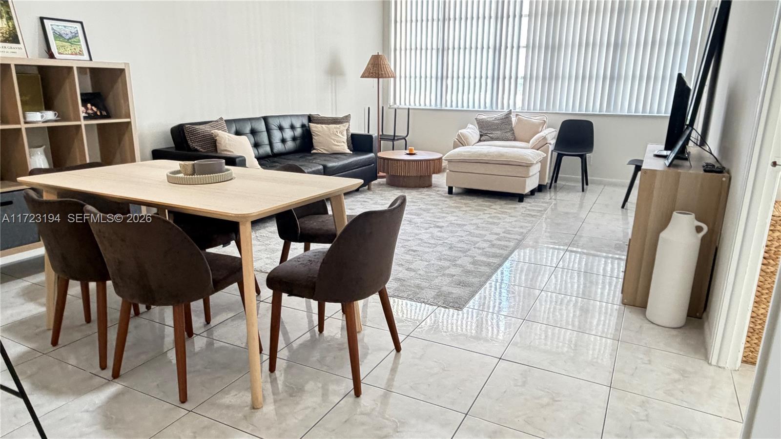 A living and dining room features tiled floors, a black sofa, and a light wood table — 1825 S Ocean Dr # 506, Hallandale Beach FL 33009, HALLANDALE BEACH, FL