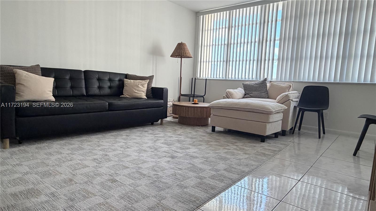 A living room features a black sofa, a beige armchair, and a circular wooden table — 1825 S Ocean Dr # 506, Hallandale Beach FL 33009, HALLANDALE BEACH, FL