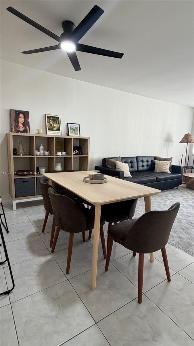 A dining area with a light wood table and dark chairs sits before a living room — 1825 S Ocean Dr # 506, Hallandale Beach FL 33009, HALLANDALE BEACH, FL