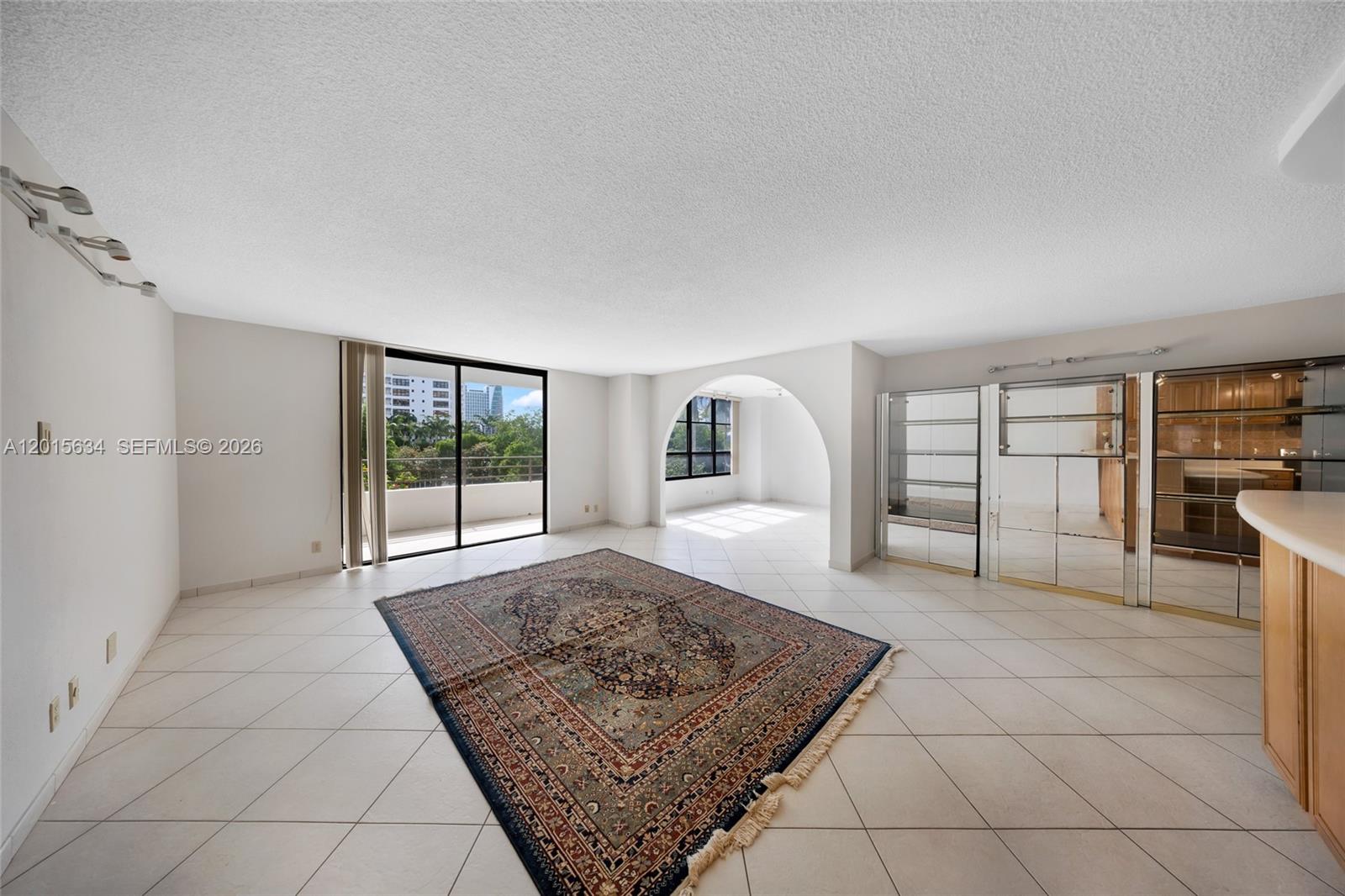 A spacious living room features white tile floors, an arched entryway, and a large rug — 600 Three Islands Blvd # 212, Hallandale Beach FL 33009, HALLANDALE BEACH, FL
