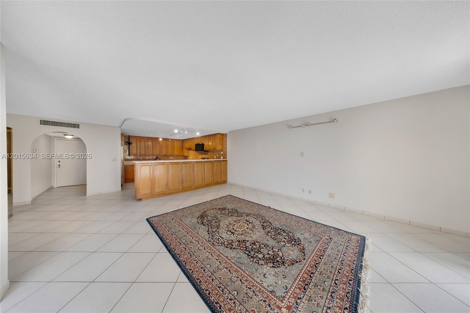 An open-concept living area features light tile flooring, a large area rug, and a kitchen — 600 Three Islands Blvd # 212, Hallandale Beach FL 33009, HALLANDALE BEACH, FL