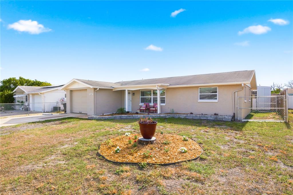 A single-story house with a tan brick exterior, a garage, and a circular front garden — 11205 GLOVER ROAD, PORT RICHEY, FL