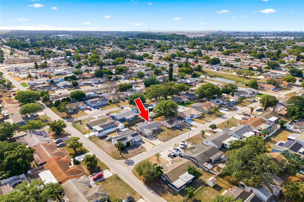 An aerial view shows a residential neighborhood with a red arrow pointing to a house — 11205 GLOVER ROAD, PORT RICHEY, FL