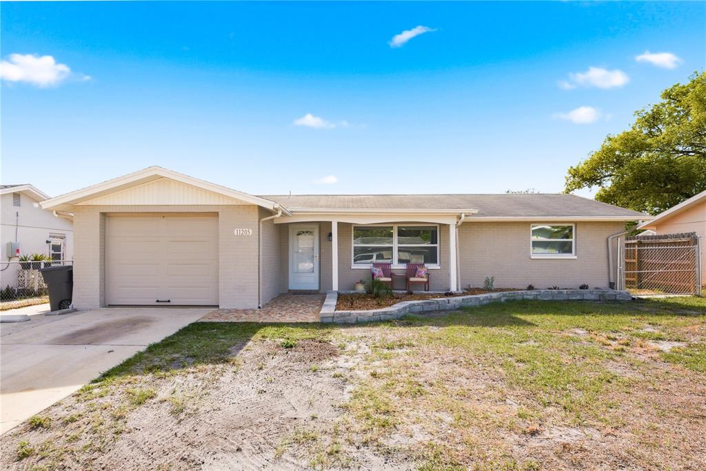A single-story brick house with a garage, front porch, and a small landscaped garden — 11205 GLOVER ROAD, PORT RICHEY, FL