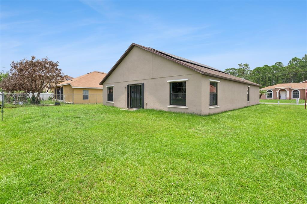 A tan, single-story house with a large backyard and a chain-link fence — 1144 CAMBOURNE DR, KISSIMMEE, FL