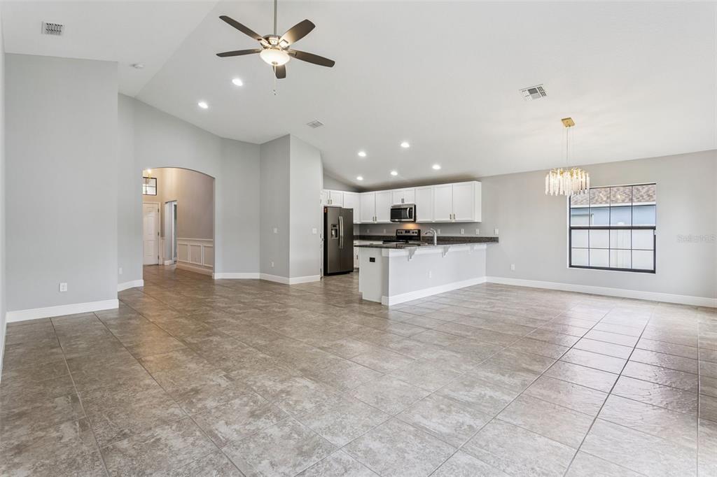 An open-concept kitchen and living area features light gray walls, tile flooring, and white cabinetry — 1144 CAMBOURNE DR, KISSIMMEE, FL