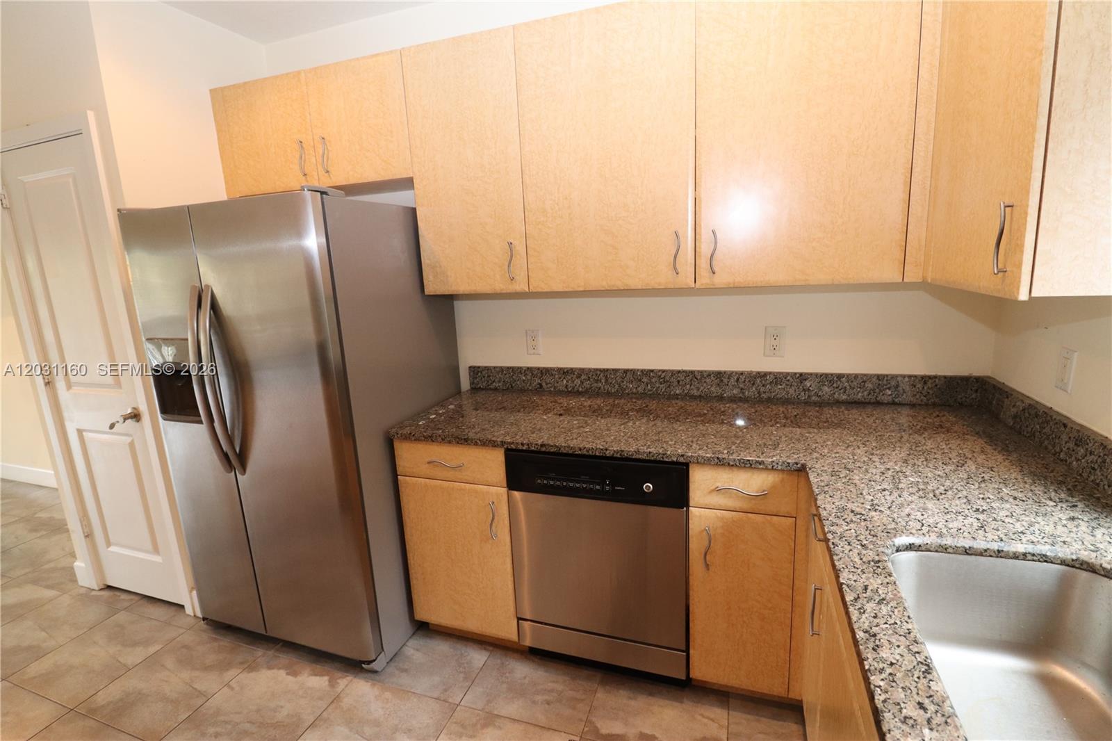 A kitchen features light wood cabinets, granite countertops, and stainless steel appliances — 609 NE 28th St # 1, Wilton Manors FL 33334, WILTON MANORS, FL