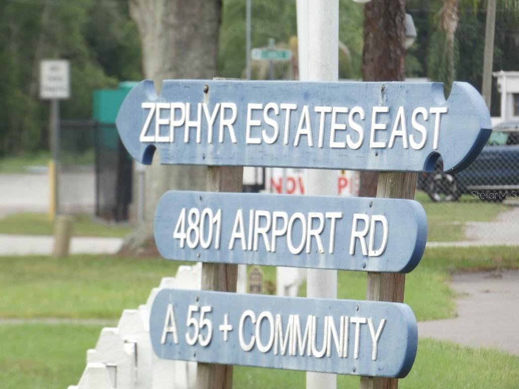 An outdoor swimming pool with a covered patio area and surrounding trees — 4801 AIRPORT ROAD UNIT 213, ZEPHYRHILLS, FL