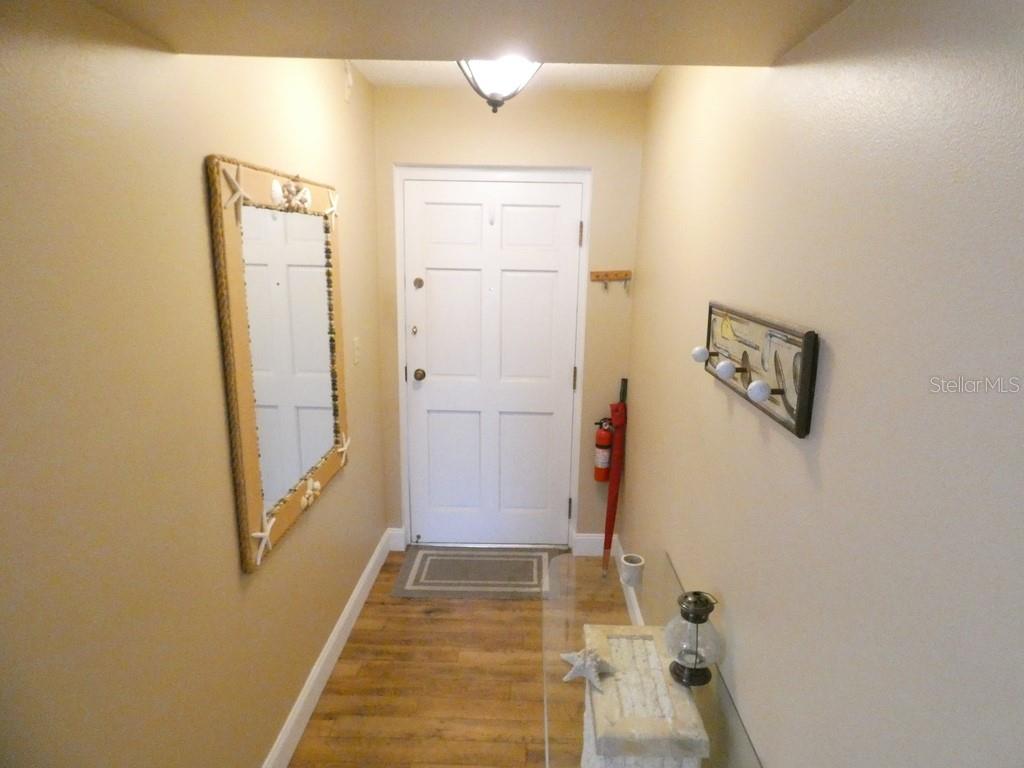 A living room features a beige sofa, patterned armchair, television, and sliding glass doors to a patio — 4801 AIRPORT ROAD UNIT 213, ZEPHYRHILLS, FL