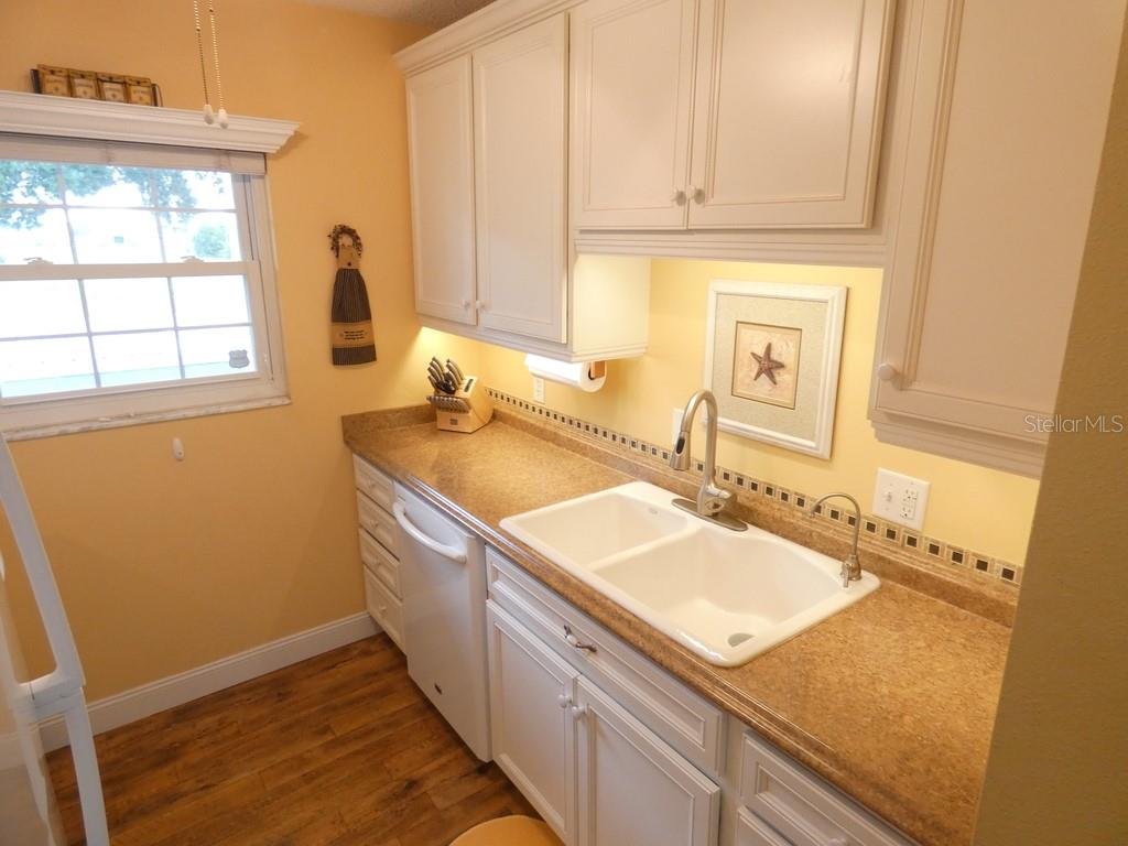 An entryway features a white door, wood-look flooring, a mirror, and a small glass table — 4801 AIRPORT ROAD UNIT 213, ZEPHYRHILLS, FL