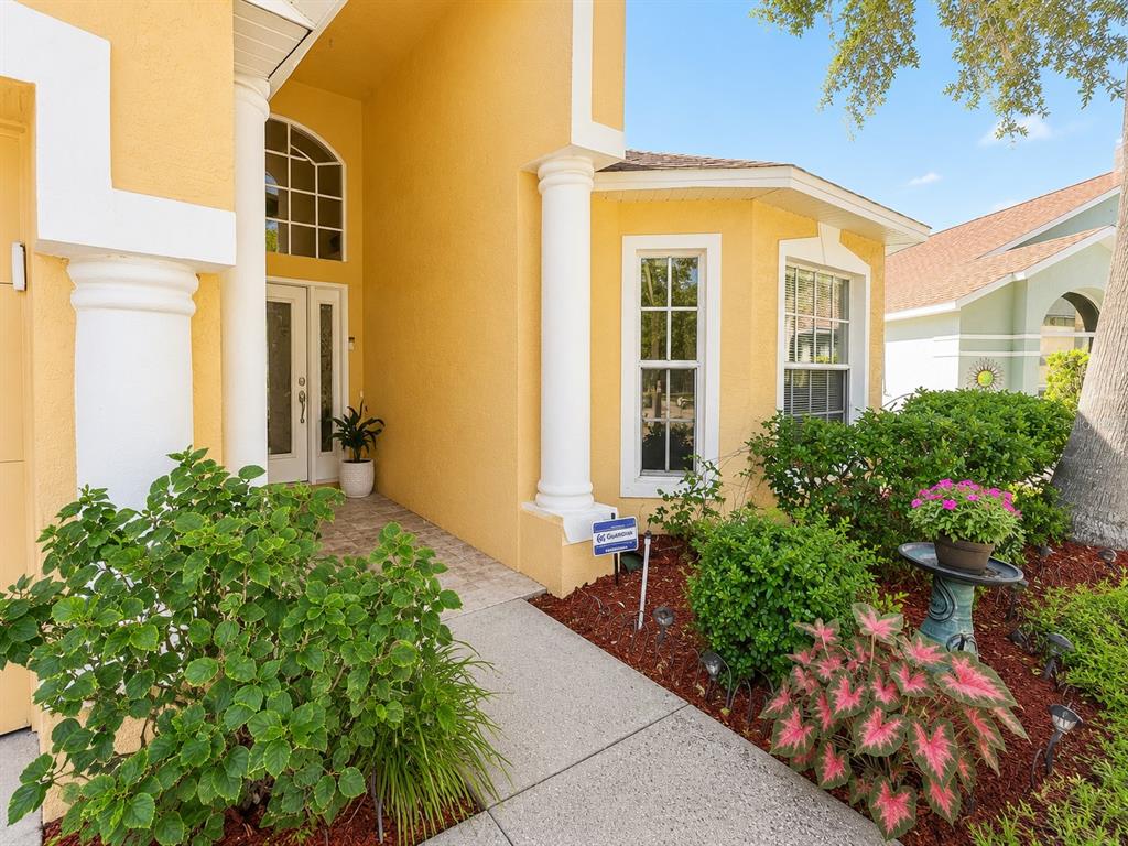 A yellow single-story house features a two-car garage, arched entryway, and a manicured front lawn — 4431 STONES RIVER COURT, NEW PORT RICHEY, FL