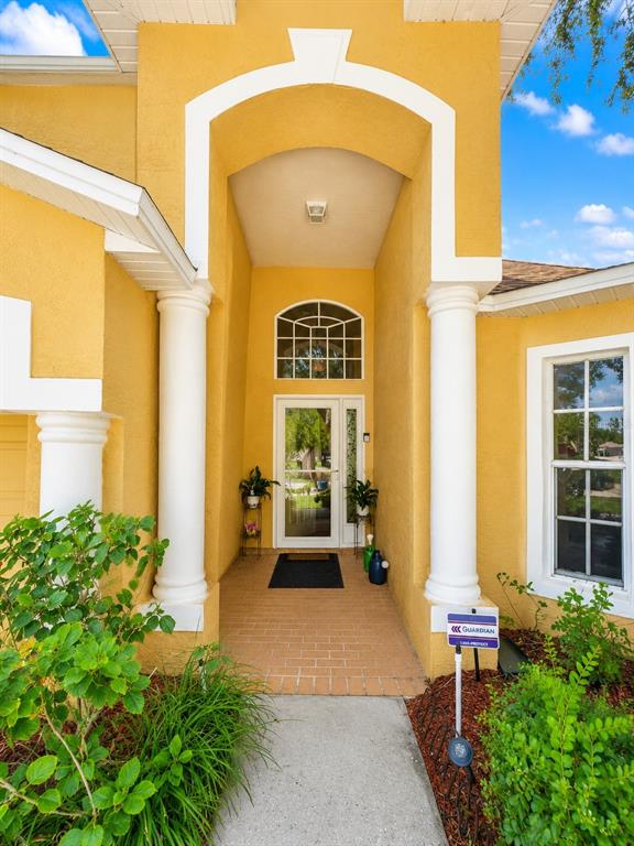 The exterior of a yellow house features a front porch with white columns and landscaping — 4431 STONES RIVER COURT, NEW PORT RICHEY, FL