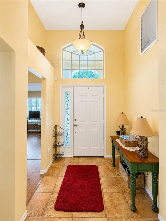 The front entrance of a yellow house features a covered porch with two white columns — 4431 STONES RIVER COURT, NEW PORT RICHEY, FL