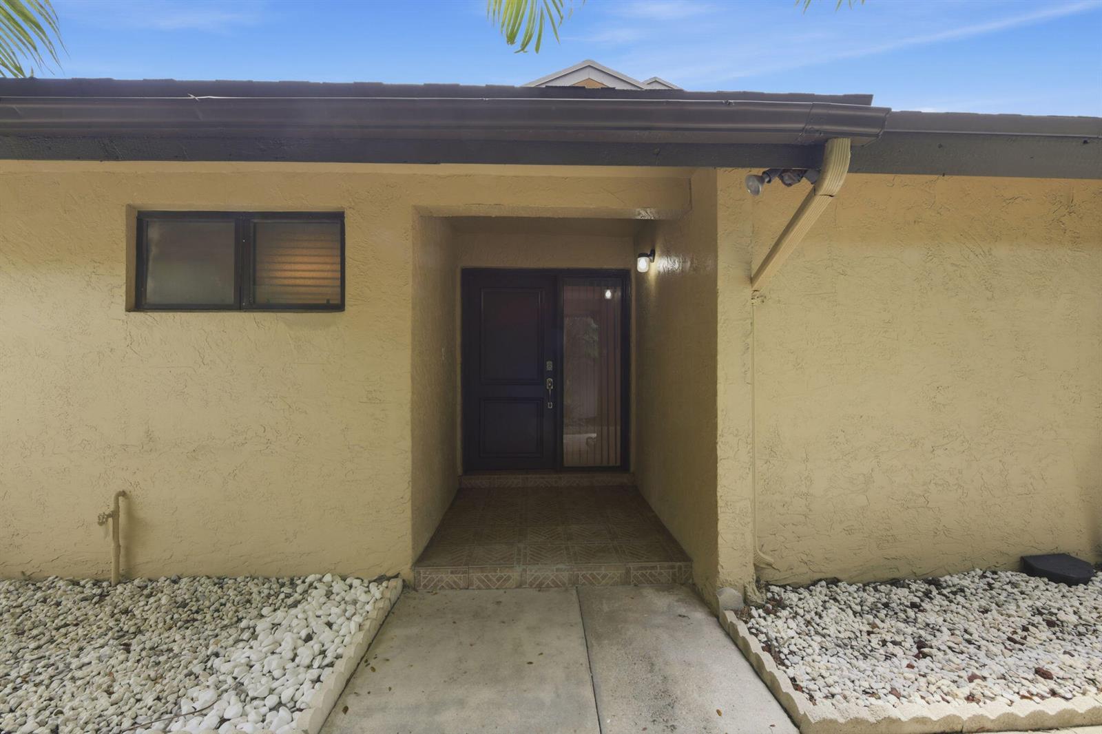 The exterior of a house features a recessed entryway with a dark door and windows — 8741 Cleary Boulevard, Plantation FL 33324, PLANTATION, FL