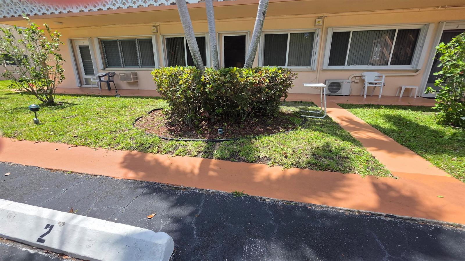 The exterior of a single-story apartment building features a landscaped lawn and parking space — 900 SW 10th Terrace # 2s, Hallandale Beach FL 33009, HALLANDALE BEACH, FL