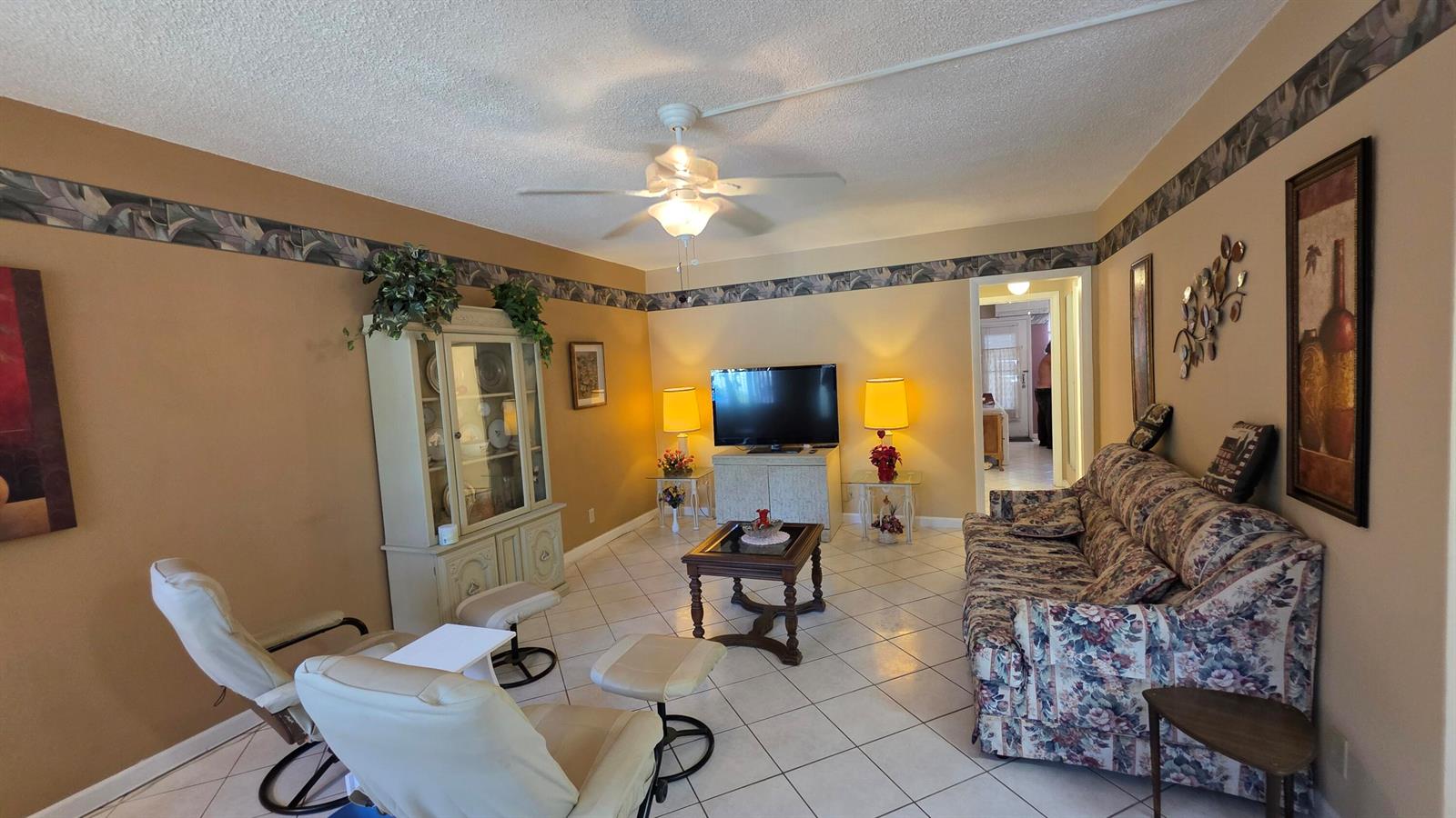 A living room features a floral sofa, two white recliners, a television, and tile flooring — 900 SW 10th Terrace # 2s, Hallandale Beach FL 33009, HALLANDALE BEACH, FL