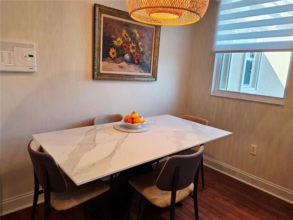 A dining room features a white marble-topped table, four chairs, and a framed floral painting — 6775 HUNTINGTON LAKES CIRCLE UNIT 202, NAPLES, FL