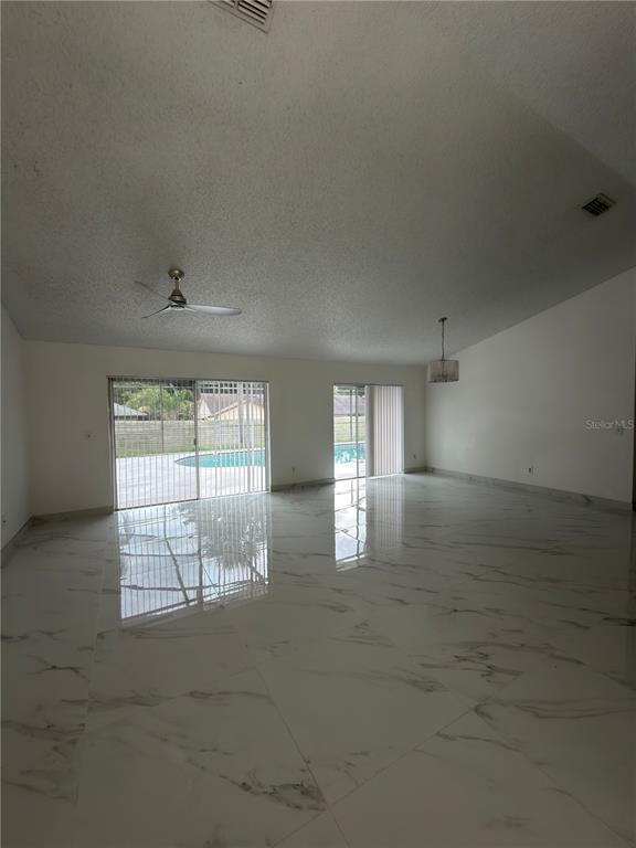 A spacious living area features white marble-look tile flooring, a ceiling fan, and sliding glass doors — 9142 SABAL PALM CIRCLE, WINDERMERE, FL