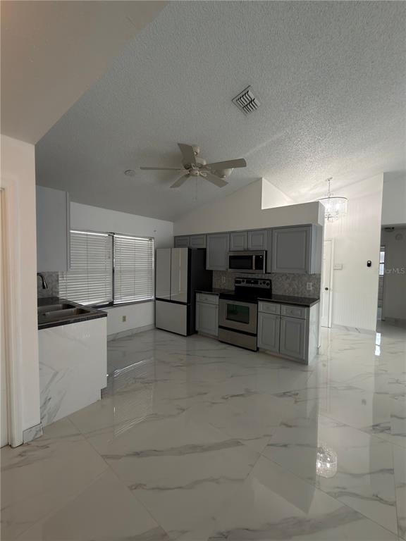 A kitchen with gray cabinets, stainless steel appliances, and white marble-patterned tile flooring — 9142 SABAL PALM CIRCLE, WINDERMERE, FL