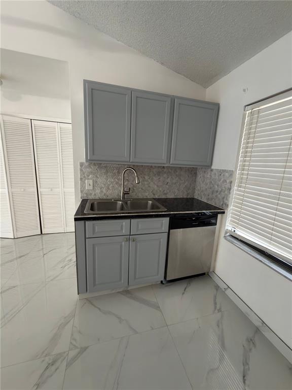 A kitchen features gray cabinets, a stainless steel dishwasher, and white marble-patterned floor tiles — 9142 SABAL PALM CIRCLE, WINDERMERE, FL