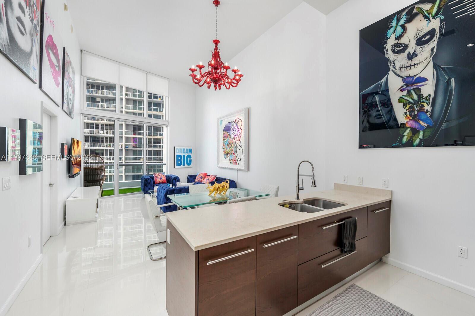 A modern open-plan kitchen and living area features dark wood cabinets and a red chandelier — 475 Brickell Ave # 2811, Miami FL 33131, MIAMI, FL