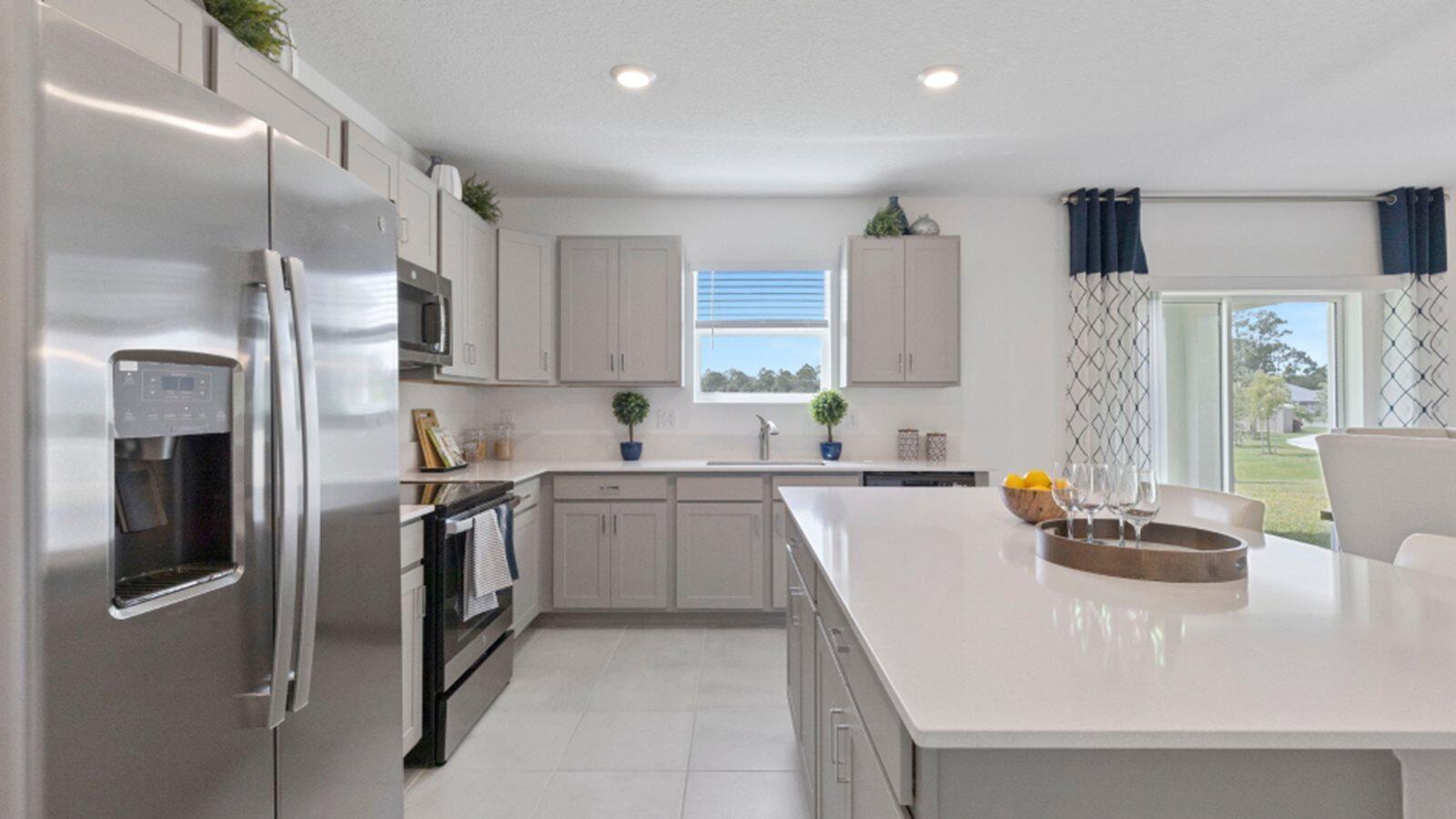 A modern kitchen features light gray cabinets, stainless steel appliances, and a large white island — 3202 Spanish Cedar Place, Fort Pierce FL 34946, FORT PIERCE, FL