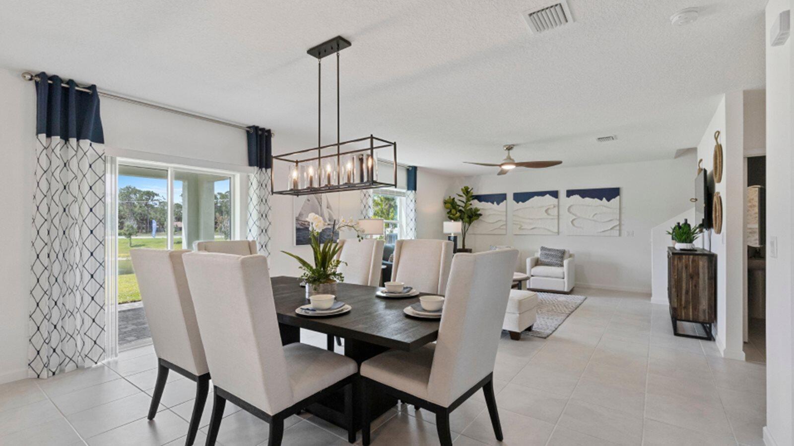 A dining area with a dark wood table and light chairs sits near a living room — 3202 Spanish Cedar Place, Fort Pierce FL 34946, FORT PIERCE, FL
