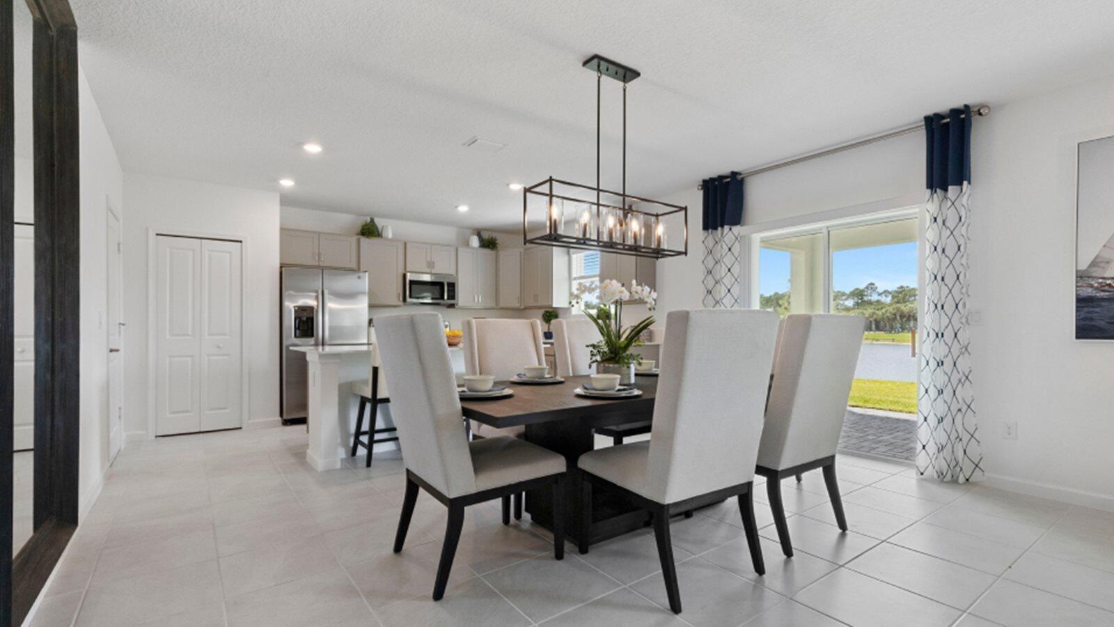 A dining area with a dark wood table and chairs sits before an open kitchen — 3202 Spanish Cedar Place, Fort Pierce FL 34946, FORT PIERCE, FL