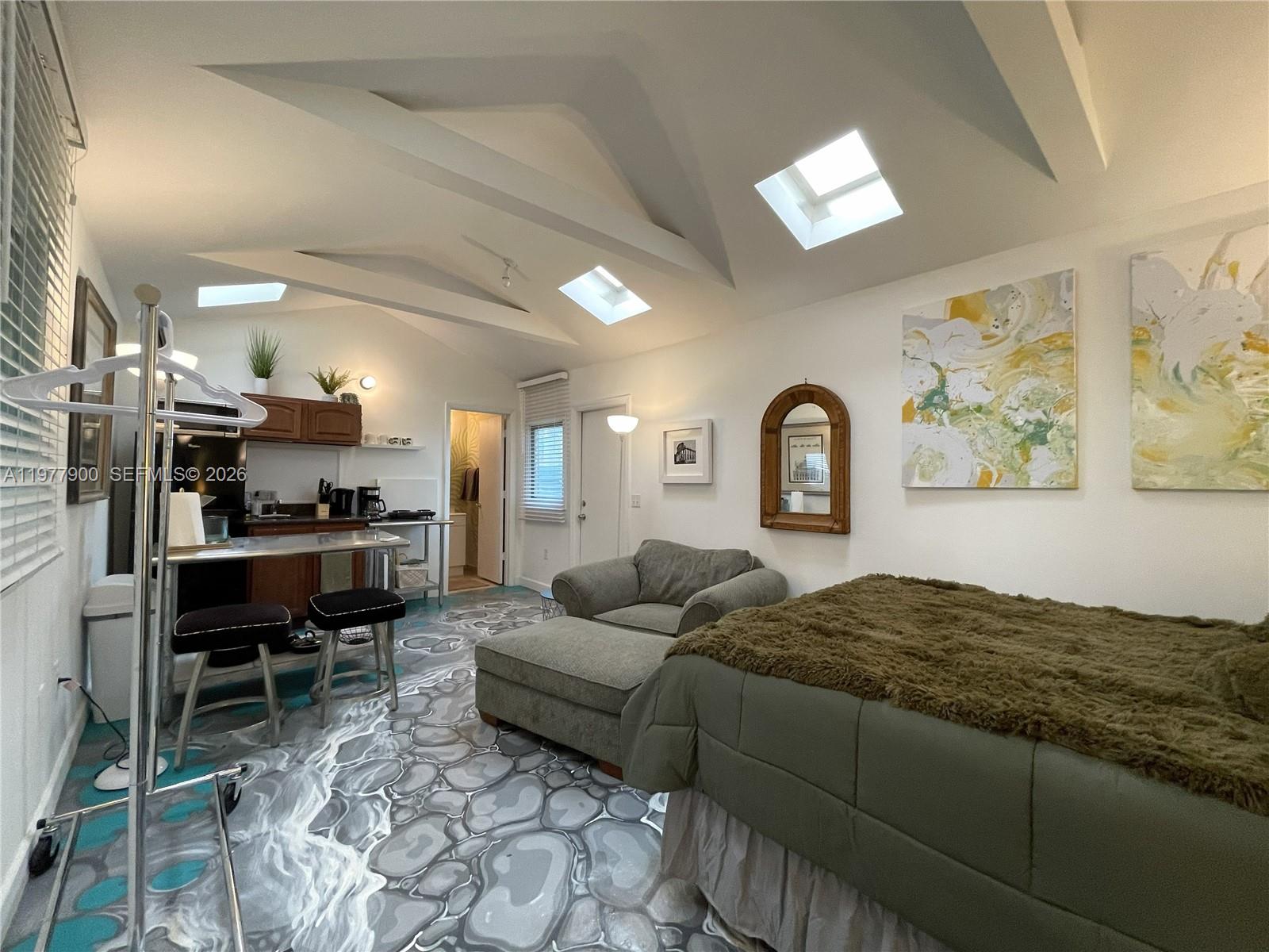 This studio apartment features a unique stone-patterned floor, vaulted ceilings with skylights, and a kitchenette — 118 NW 24th St, Miami FL 33127, MIAMI, FL