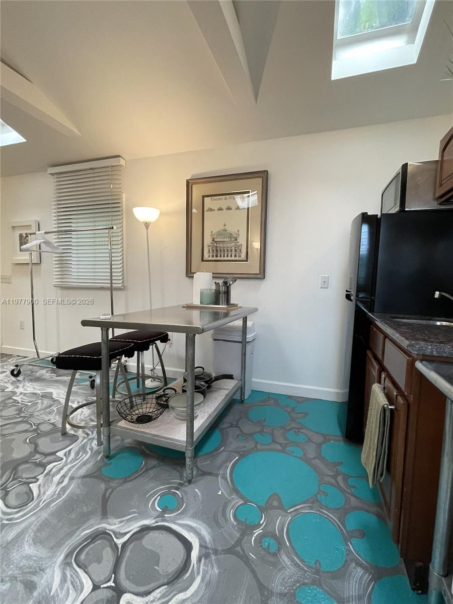 A kitchen features a stainless steel island, dark cabinets, and a unique blue-and-grey patterned floor — 118 NW 24th St, Miami FL 33127, MIAMI, FL