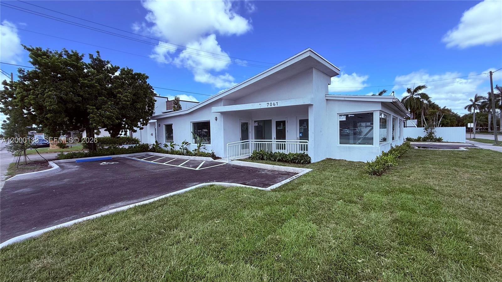 A white, single-story commercial building with a sloped roof and a paved parking lot — 7061 Taft St # C, Hollywood FL 33024, HOLLYWOOD, FL