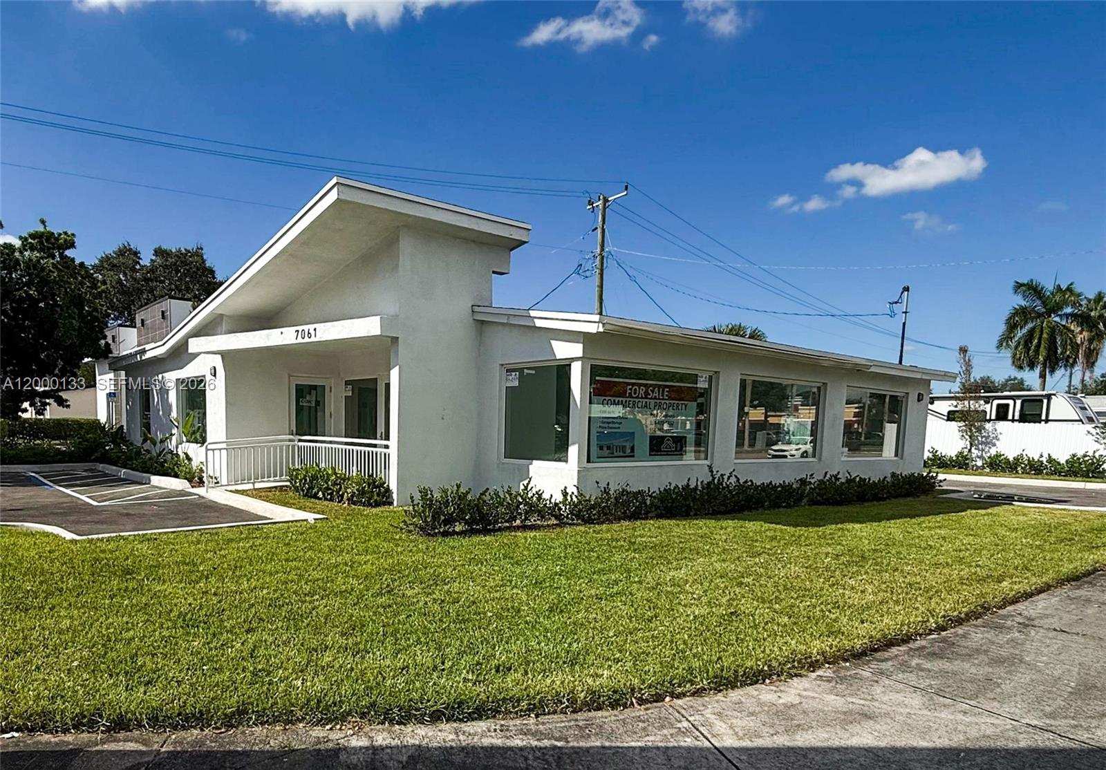 A white, single-story commercial building with large windows sits on a grassy lot — 7061 Taft St # C, Hollywood FL 33024, HOLLYWOOD, FL