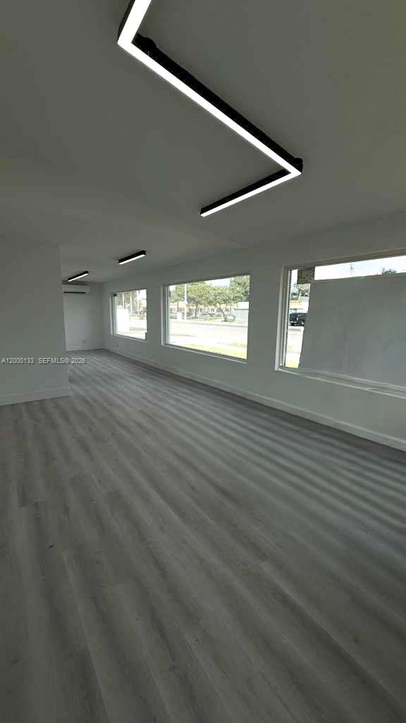 An empty room features light wood-look flooring, white walls, and modern linear ceiling lighting — 7061 Taft St # C, Hollywood FL 33024, HOLLYWOOD, FL