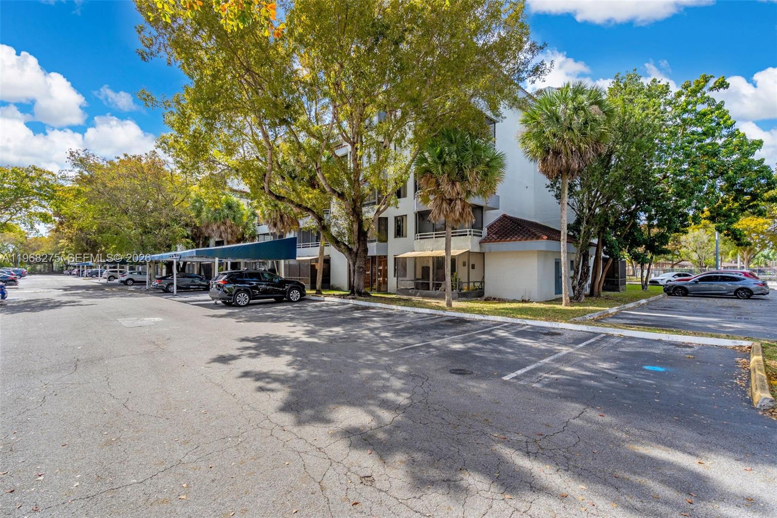 A multi-story apartment building with a parking lot and covered carports in front — 8305 SW 152nd Ave # 107, Miami FL 33193, MIAMI, FL