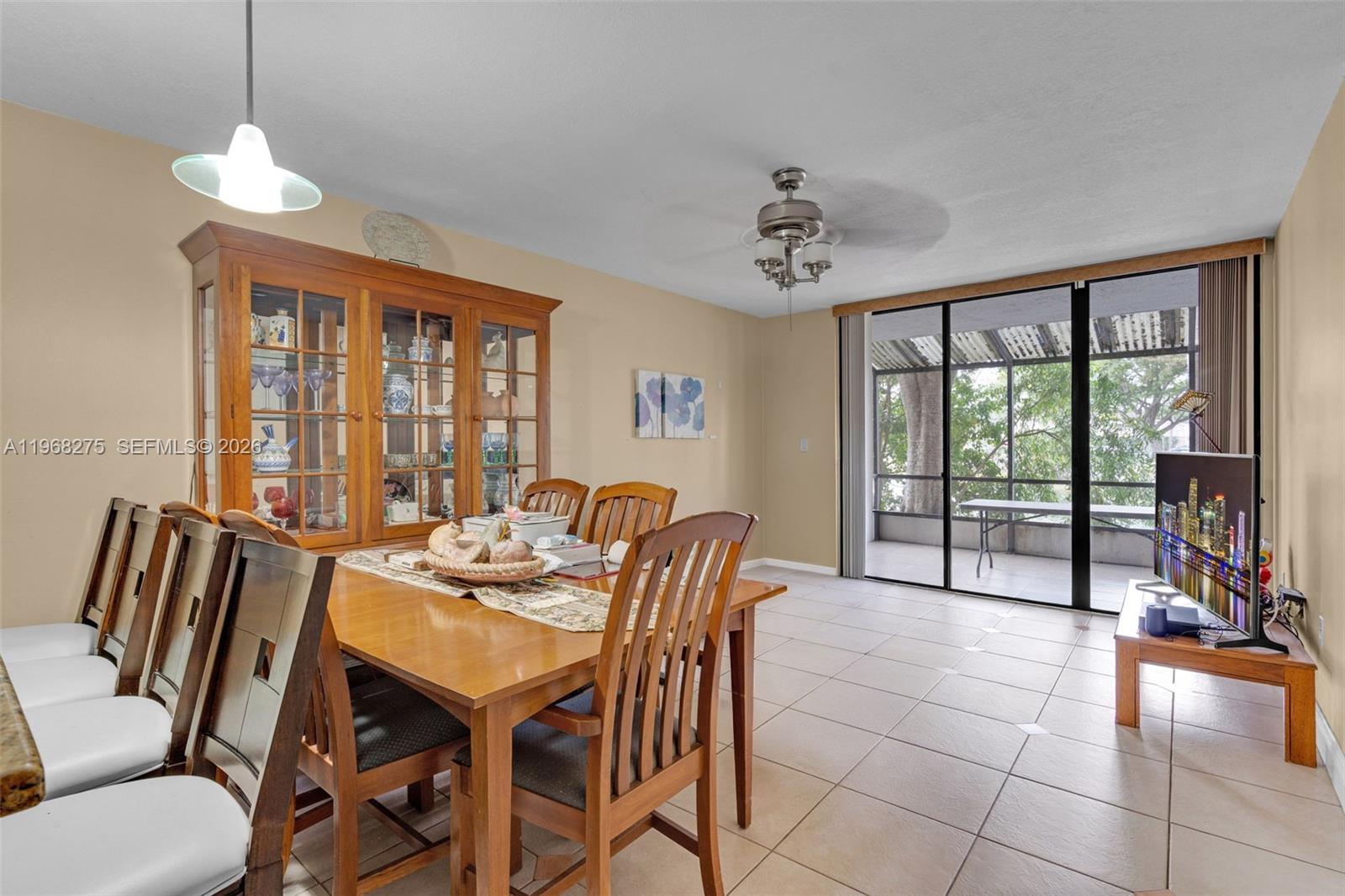 A dining area features a wooden table, hutch, tile flooring, and sliding glass doors — 8305 SW 152nd Ave # 107, Miami FL 33193, MIAMI, FL