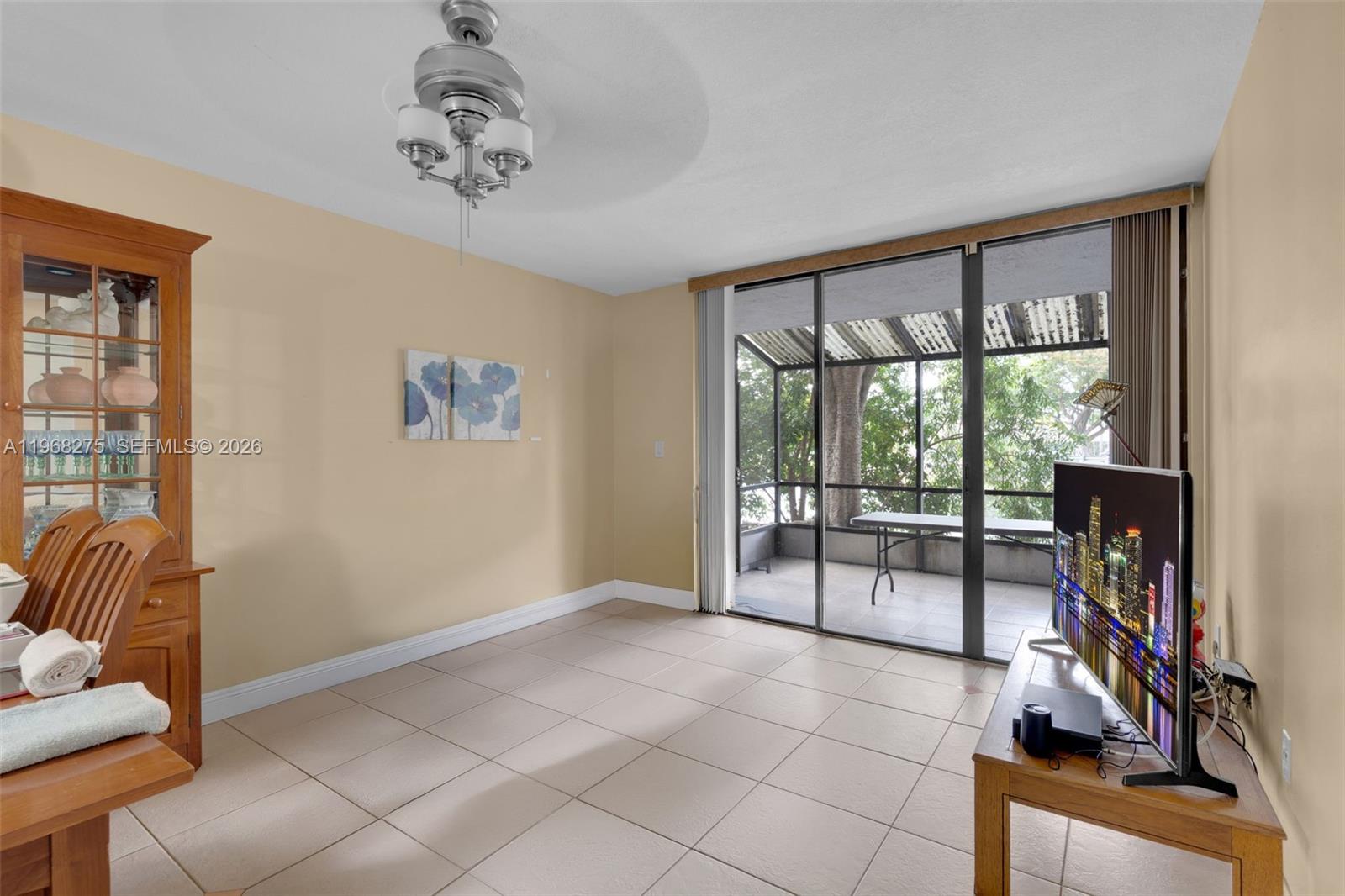 A living room with tile floors, a ceiling fan, and sliding doors to a screened balcony — 8305 SW 152nd Ave # 107, Miami FL 33193, MIAMI, FL