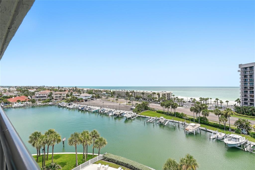 An elevated view of a marina, a coastal road, and the ocean from a balcony — 1651 SAND KEY ESTATES COURT UNIT 78, CLEARWATER BEACH, FL