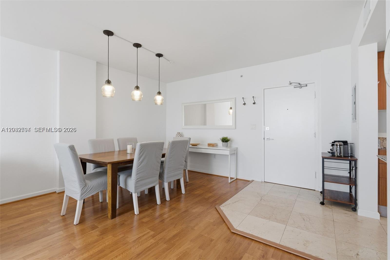 A dining area features a wooden table, six chairs, pendant lighting, and hardwood flooring — 10275 Collins Ave # 718, Bal Harbour FL 33154, BAL HARBOUR, FL