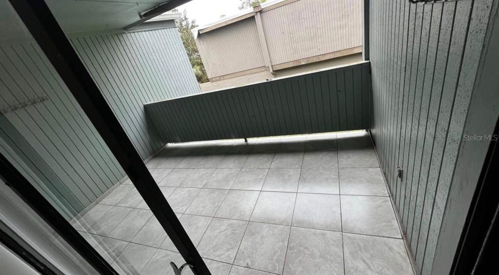 A covered balcony features light-colored square floor tiles and vertical wood-paneled walls — 707 SW 75TH ST UNIT 109, GAINESVILLE, FL