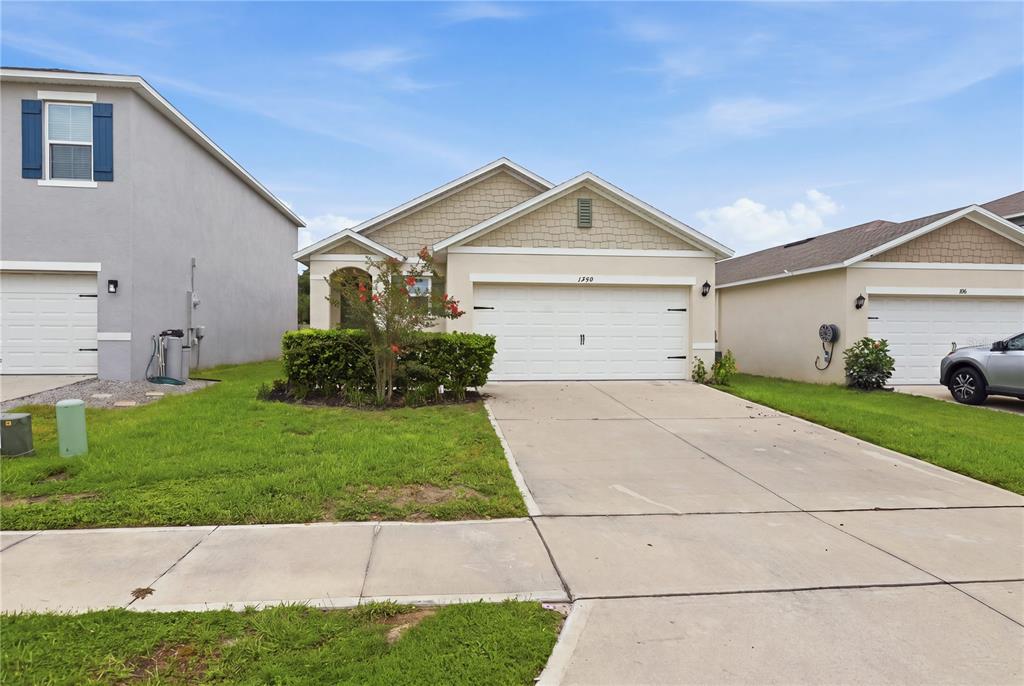 A single-story suburban house features a two-car garage, a concrete driveway, and a small lawn — 1749 SHADOW TRACE WAY, DELAND, FL
