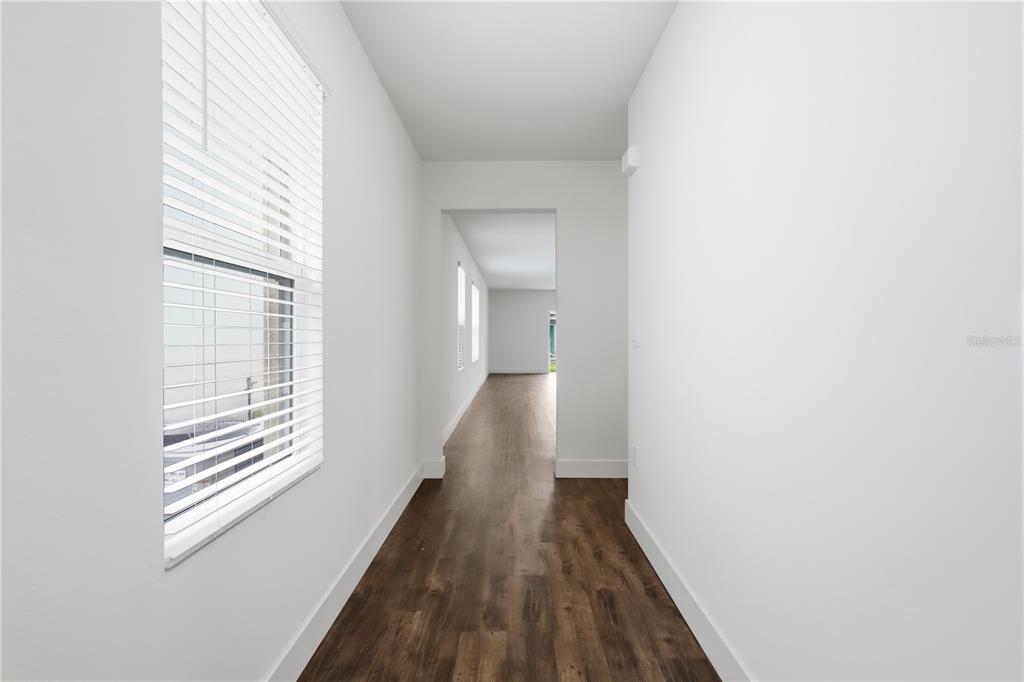 A hallway with white walls, wood-look flooring, and a window with white blinds — 1749 SHADOW TRACE WAY, DELAND, FL
