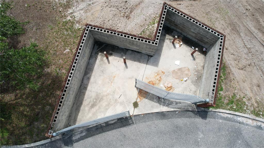 An aerial view of an outdoor concrete dumpster enclosure with metal gates and block walls — 1407 HAVENDALE BOULEVARD NW, WINTER HAVEN, FL
