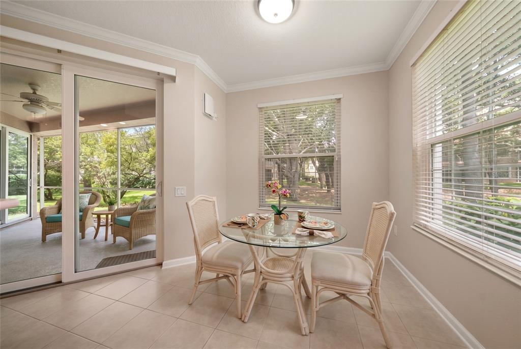 A dining area with a glass table, wicker chairs, tile floors, and a sliding glass door — 853 LANTERN WAY, CLEARWATER, FL