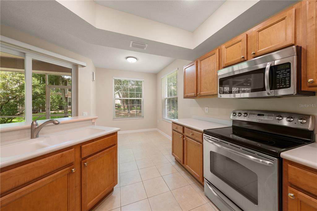 A kitchen with light-colored tile floors, wooden cabinets, stainless steel appliances, and a sliding door — 853 LANTERN WAY, CLEARWATER, FL