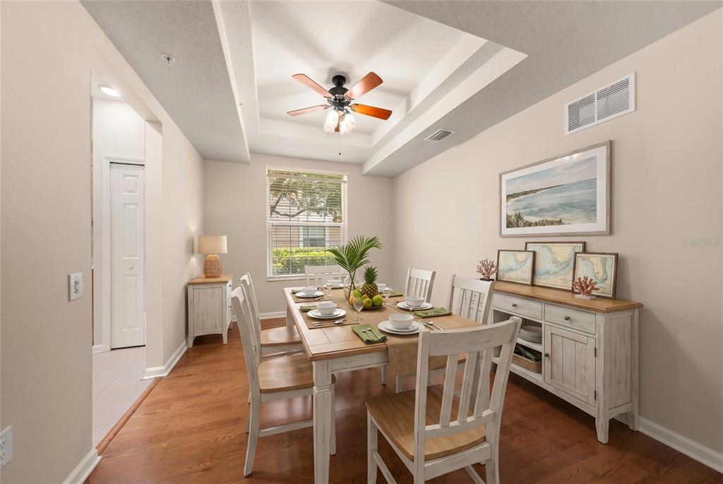 A dining room with a tray ceiling, wooden table, chairs, and a white sideboard — 853 LANTERN WAY, CLEARWATER, FL
