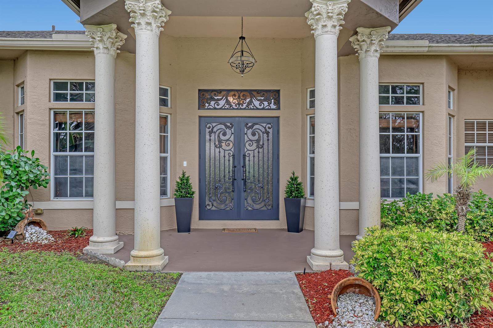 The front entrance features a double door with iron scrollwork, two columns, and potted plants — 14042 88th Place N, FL 33470, FL